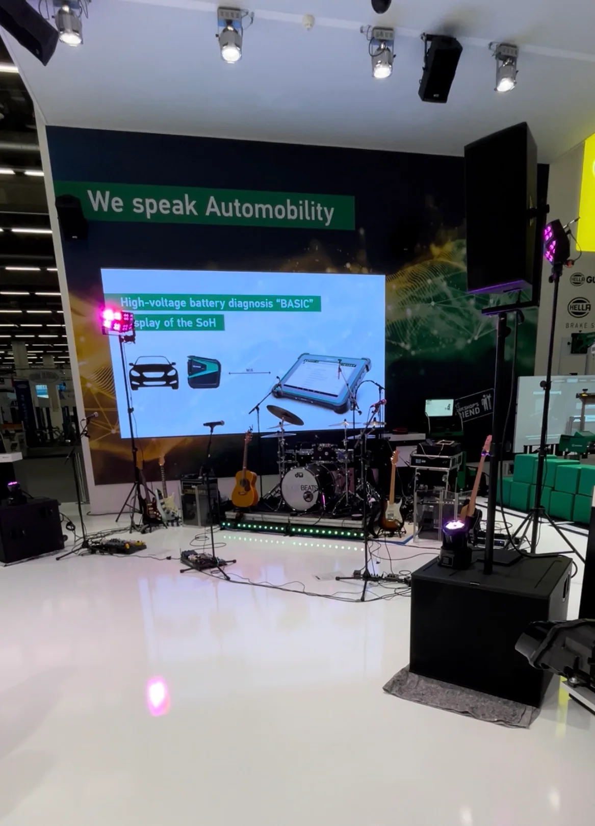 Aufgebaute Bühne der GOODBEATS auf einem Messestand: Schlagzeug, Gitarren und Mikrofone vor einer großen Präsentationsleinwand.